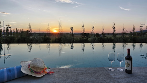 A poolside view with a sunset, a bottle of wine, and two glasses. - Wonderful Family Suite in Tuscany near Pisa and Florence - 2 Bedrooms 4 PL (Palaia)
