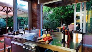 A modern kitchen with a stainless steel countertop, a built-in oven, and a window overlooking a garden. - Wonderful Family Suite in Tuscany near Pisa and Florence - 2 Bedrooms 4 PL (Palaia)