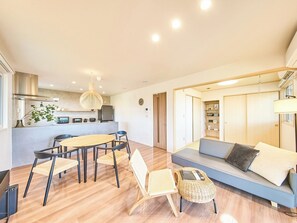 Ett modernt vardagsrum med en matplats, en soffa, ett litet bord och ett kök i bakgrunden.