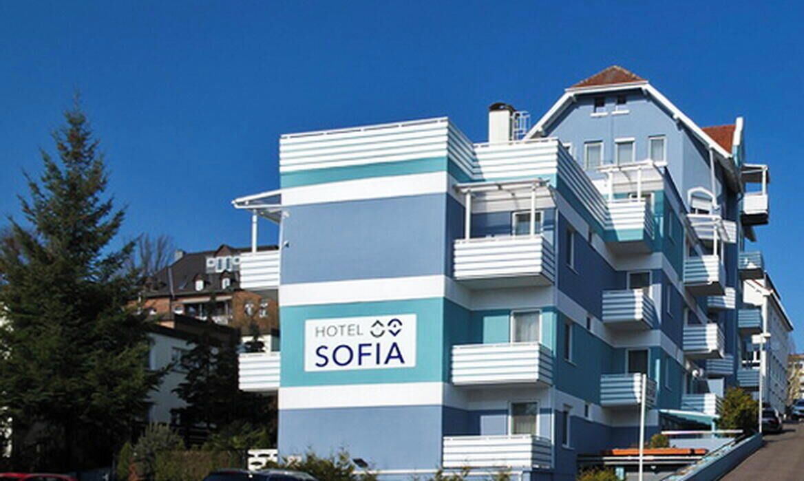 Ein Hotel namens 'HOTEL SOFIA' mit modernem Design, Balkonen und blauem Himmel.