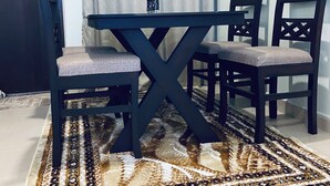 Un coin repas avec une table et des chaises en bois foncé, un tapis à motifs et un rideau.