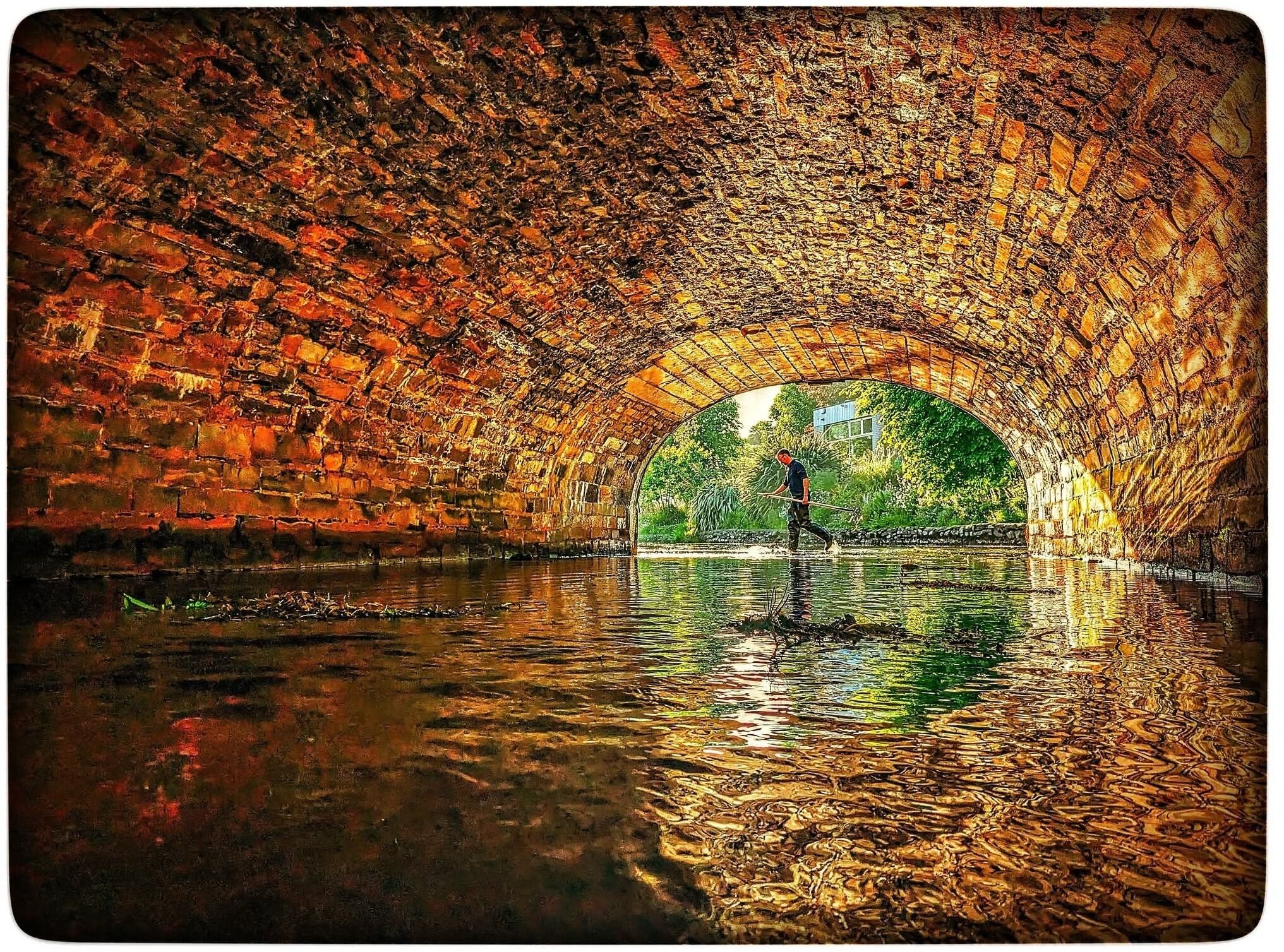 A stone bridge over water with a person standing in the middle.
