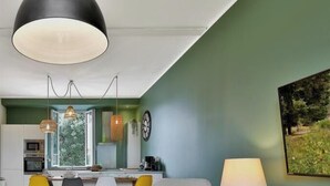 A modern kitchen with a large window, pendant lights, and a dining area with yellow chairs.