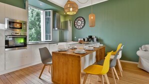 A modern kitchen with built-in appliances, a dining area with a wooden island, and a view through large windows.