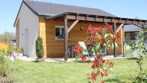 A wooden house with a covered patio, a small garden, and a window. - Comfortable 44 M2 house, 3* Gîte de France, 100 m from stock pond. (Kerprich-aux-Bois)