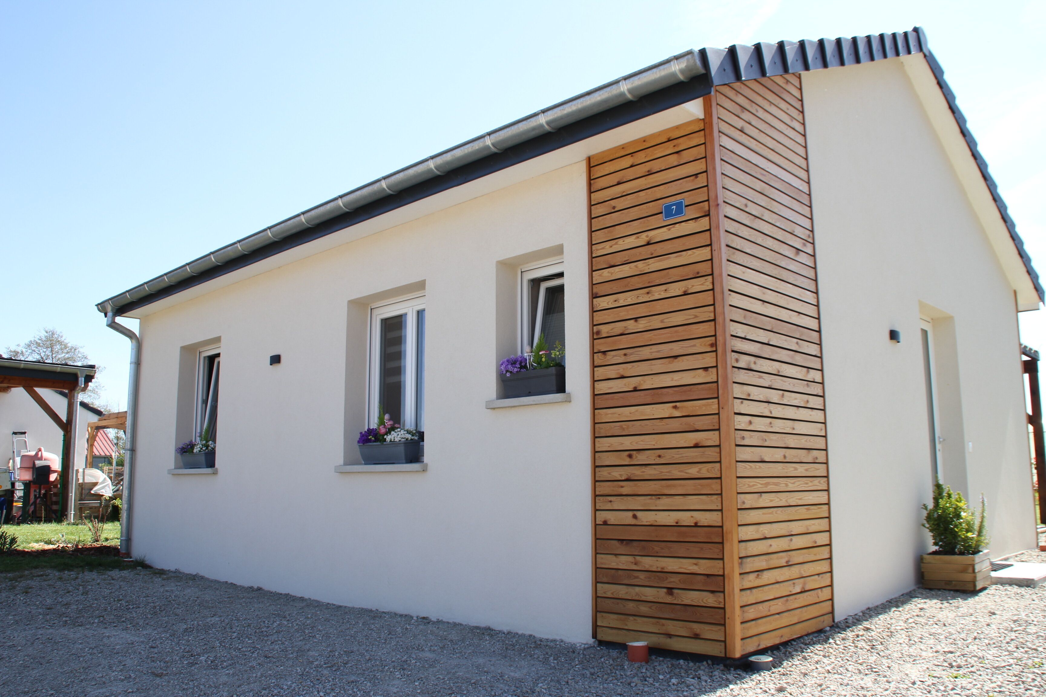 Un bâtiment d’un seul étage, doté d’un toit en pente, d’un chambranle en bois et de trois fenêtres ornées de jardinières.