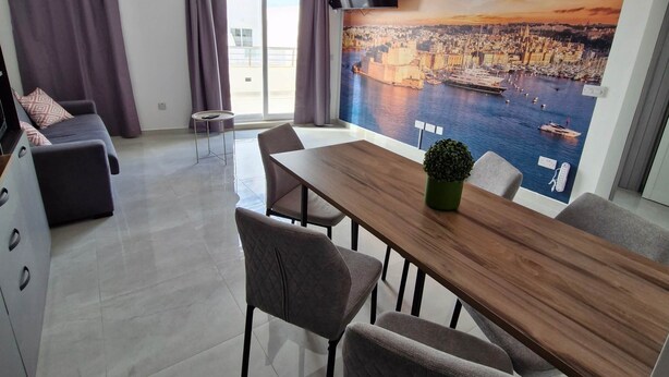 A modern living room with a dining area, a flat-screen TV, and a cityscape mural. - Penthouse Penthouse Green House A27 - Green style (Saint Paul's Bay)