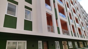 Edifici d'edificis amb balcons, grans finestres i façana verda.
