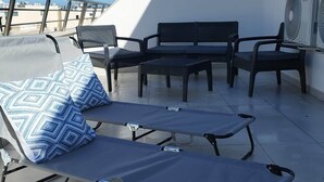 A rooftop terrace with a lounge chair, a small table, and two chairs. - Penthouse Penthouse Green House A27 (Saint Paul's Bay)