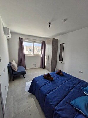 Ein Hotelzimmer mit Bett, Stuhl, Fenster und Deckenventilator.