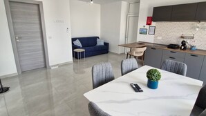 Een moderne woonruimte met een eethoek, een bank, een keuken en een deur.