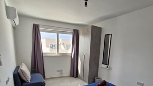 Een hotelkamer met een bed, een stoel, een raam en een plafondventilator.