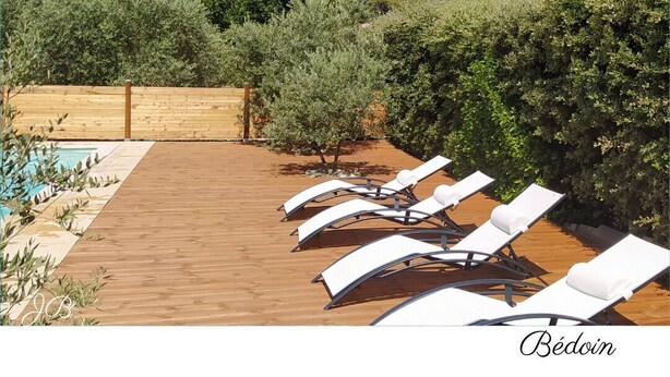 A wooden deck with lounge chairs and a pool, surrounded by greenery and mountains in the background. - Magnificent villa at the foot of Mont Ventoux (Bédoin)