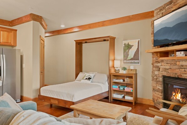 A bedroom with a four-poster bed, a fireplace, a television mounted on the wall, and a bookshelf. - 1BR Condo w/ Stunning Long-Range Views, Deck + Hot Tub / Pool / Gym - Near Boone (Boone)