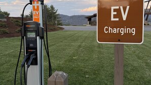Une borne de recharge pour véhicules électriques, avec un panneau indiquant qu’il s’agit d’un espace réservé à la recharge de ces véhicules.