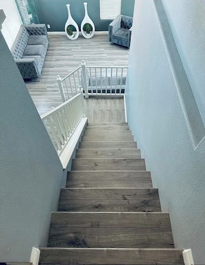 A wooden staircase with a white railing, leading to a seating area with a grey sofa and two white vases with plants. - Villa glamour in las vegas (Las Vegas)