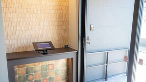 A reception desk with a digital screen, a tiled wall, and a glass door with a metal handle. - THE NINE STATES HOTEL TOJINMACHI (Fukuoka)