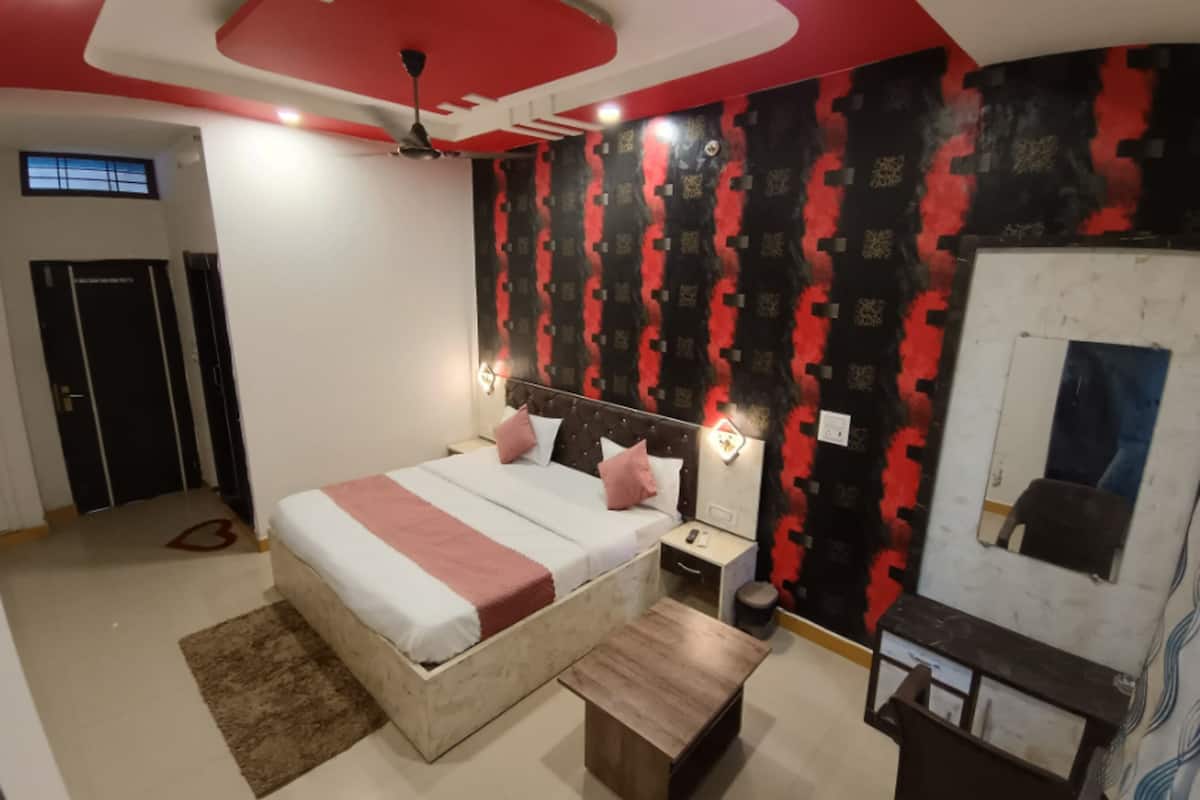Une chambre à coucher comprenant un lit, des tables de chevet, une commode, un ventilateur de plafond, une lampe fixée au mur et une porte.