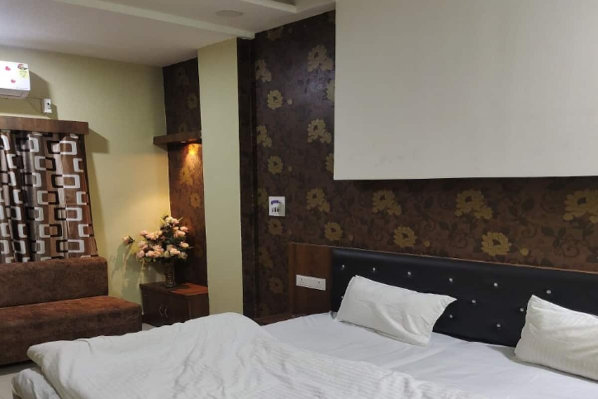 Une chambre à coucher avec un grand lit, une table de chevet, une commode et un téléviseur fixé au mur.