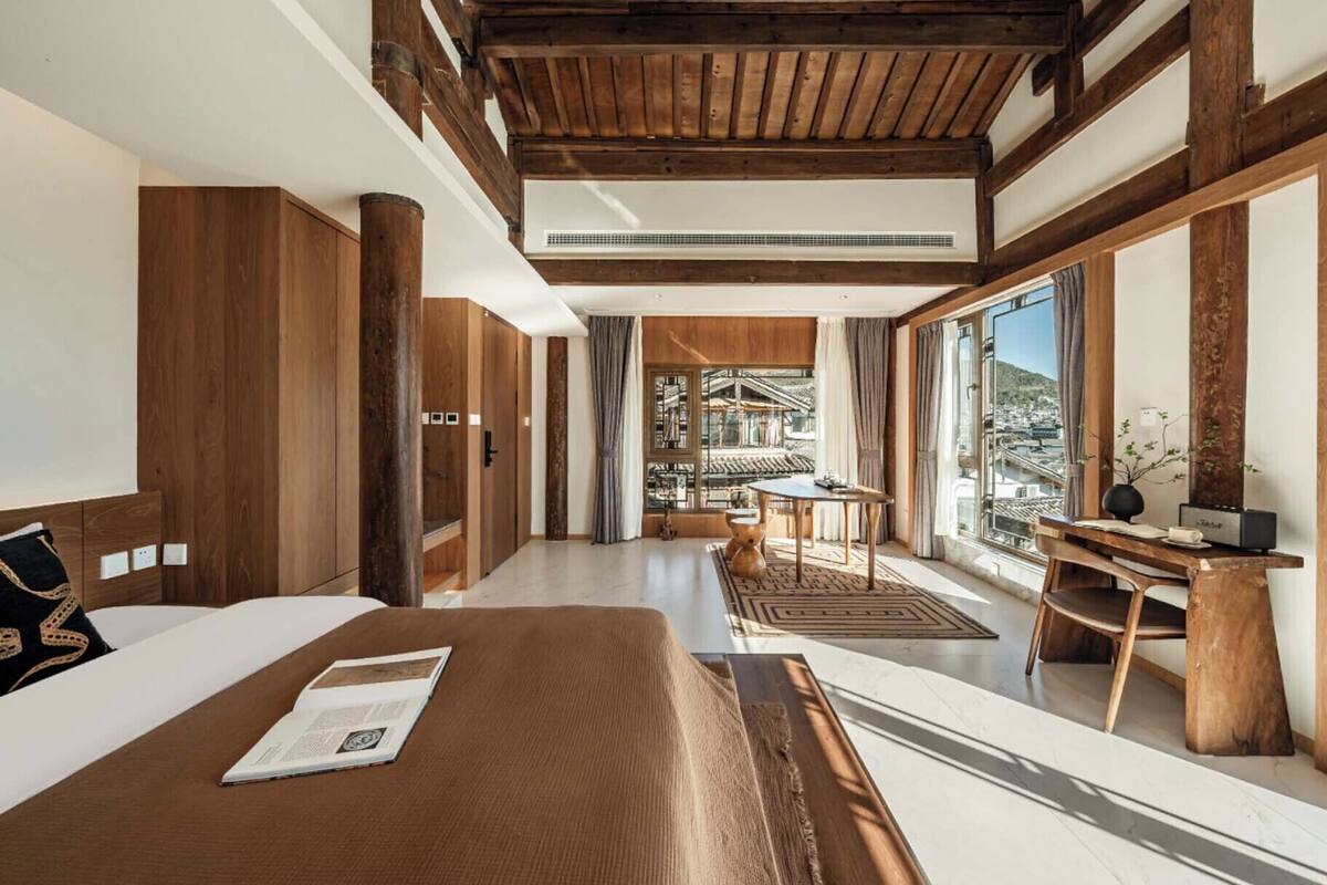 A hotel room with a large bed, a desk, and a view of a traditional building.
