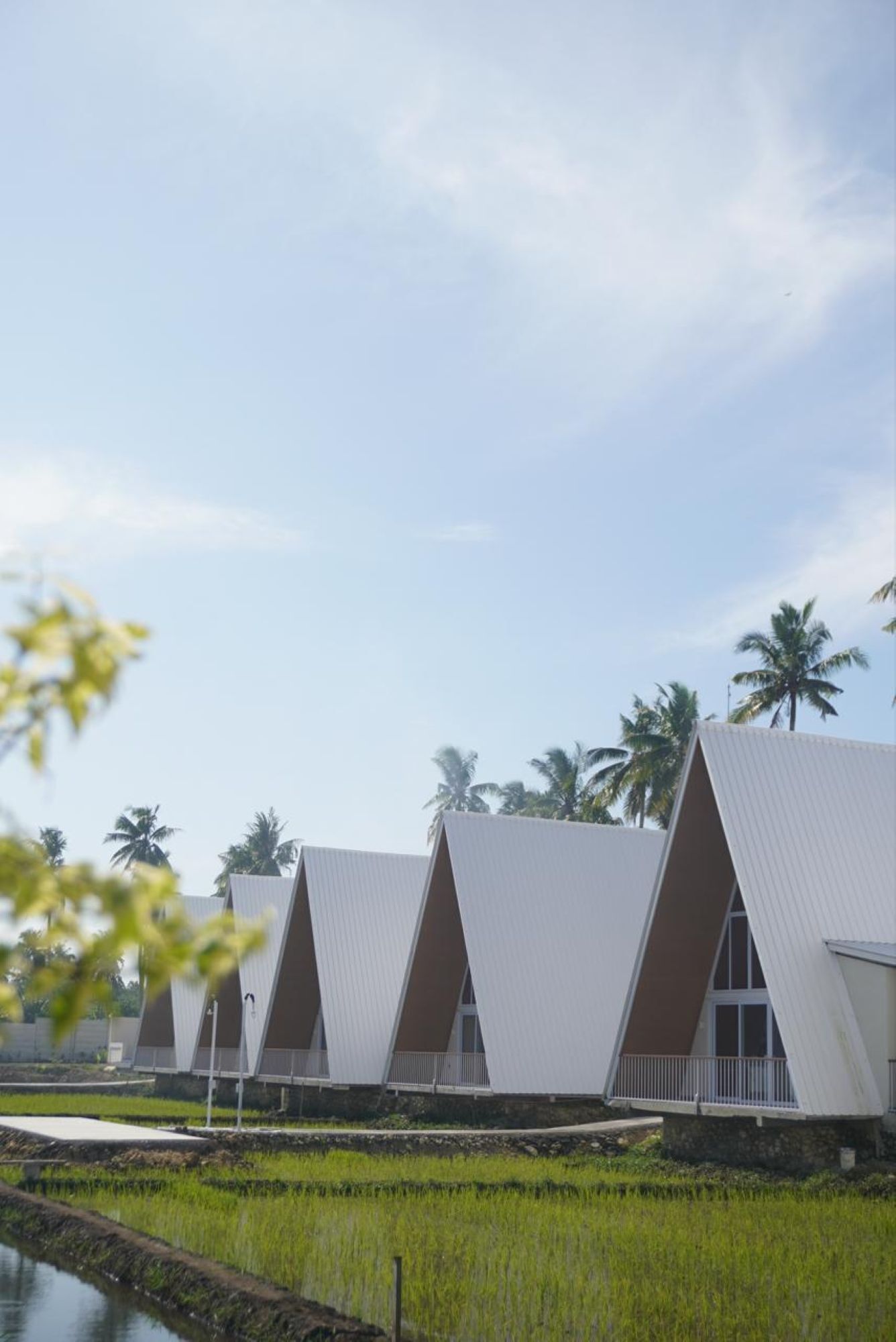 Una hilera de edificios modernos con techos triangulares y un canal de agua delante.