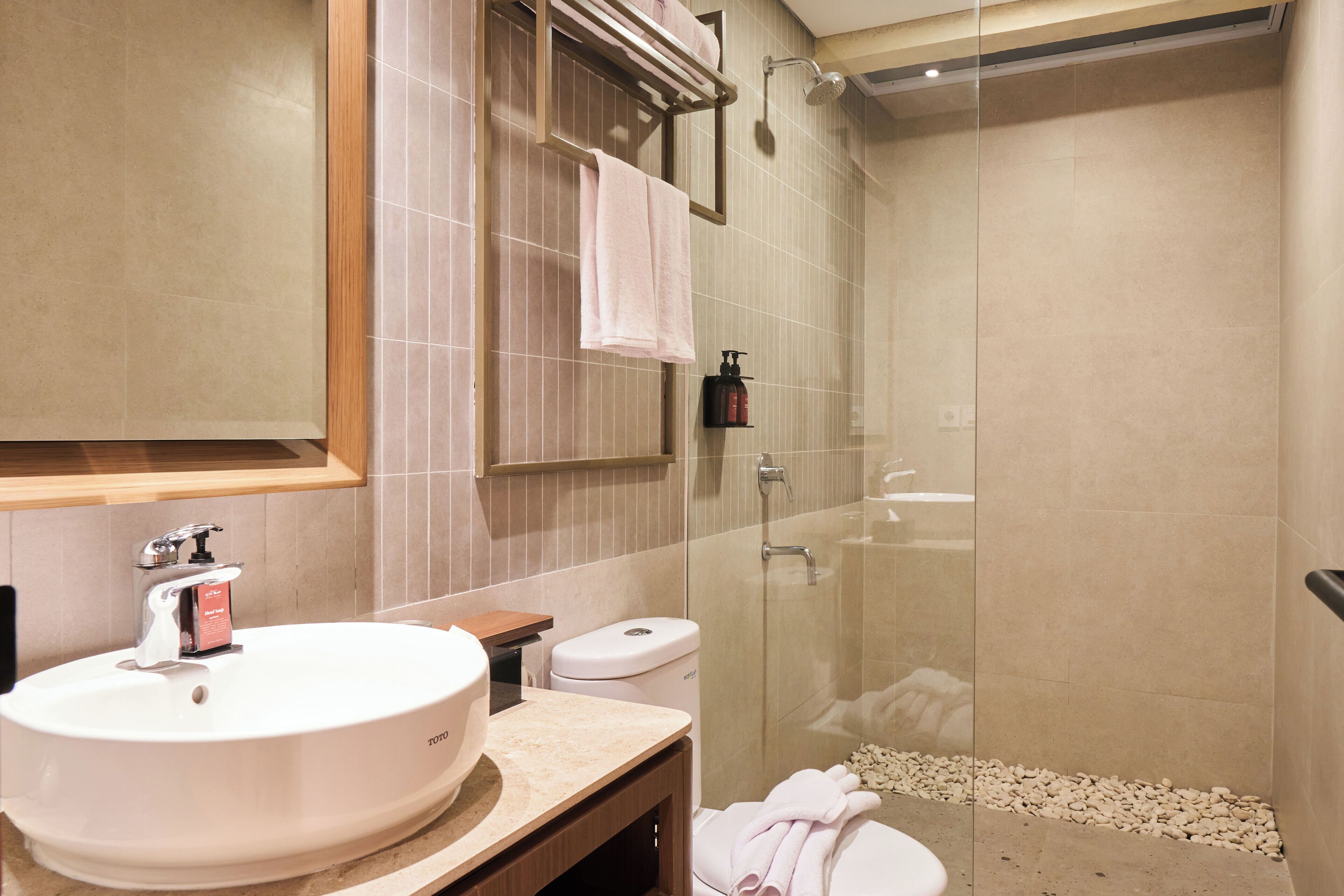 Een moderne badkamer met een wastafel, toilet en een douchecabine met glazen wanden.