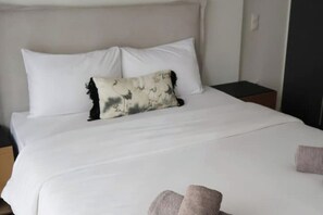 Een opgemaakt bed met witte lakens en een decoratief kussen.