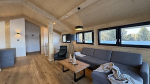 Un interior moderno con pisos de madera, un sofá, una mesa de centro y una lámpara trípode.