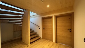 Una escalera de madera que lleva a un rellano con dos puertas de madera.