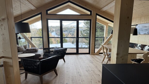 Ein geräumiger Raum mit hoher Decke, großen Fenstern und Holzvertäfelung.