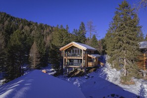 A wooden cabin with a balcony, surrounded by snow and trees. - Superior Chalet with Sauna & Hot Tub (Turrach)