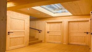 Un intérieur en bois, avec une lucarne, des portes en bois et un escalier.