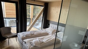 Quarto com cama, uma cadeira e vista para o exterior.
