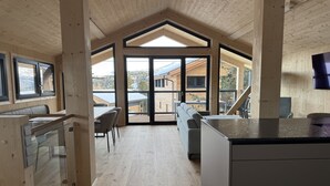 Um interior moderno com área de jantar, cozinha e amplas janelas que oferecem vista.