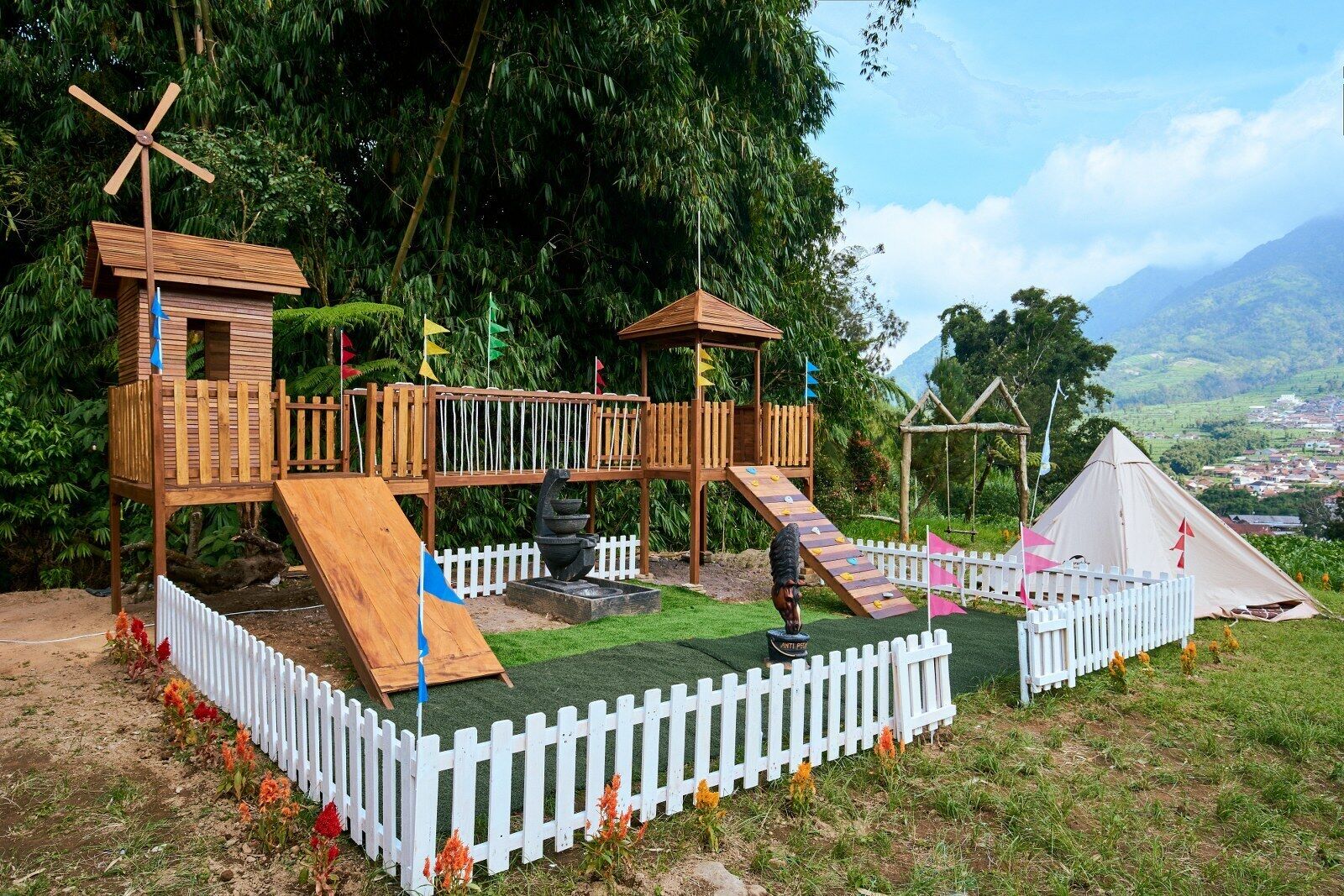 A playground with wooden structures, slides, and a white picket fence.