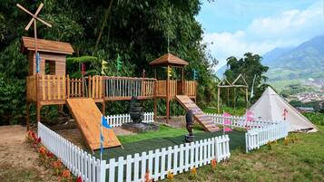 A playground with wooden structures, slides, and a white picket fence.