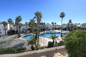 Une piscine entourée de palmiers et de bâtiments blancs.