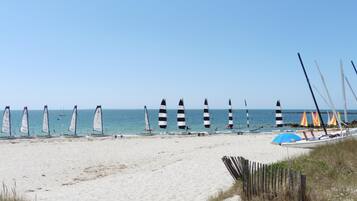 Una spiaggia con attrezzatura da windsurf e una barca.