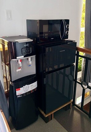 Eine kleine Küchenzeile mit Kühlschrank, Mikrowelle und Wasserspender.
