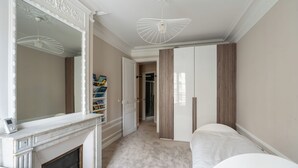 A bedroom with a fireplace, a walk-in closet, and a door leading to a bathroom. - Bright And Spacious 3BDR Apt Near Eiffel Tower (Paris)