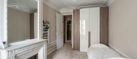 Une chambre avec une cheminée, un dressing et une porte donnant sur une salle de bain.