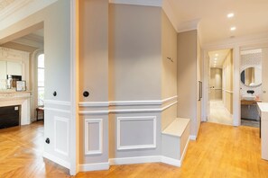 Ein modernes Interieur mit Holzboden, einer weißen Tür mit schwarzem Griff und einem Flur, der zum Badezimmer führt.