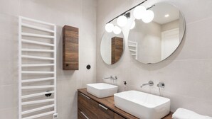 A modern bathroom with two sinks, a vanity, a mirror with lights, and a towel rack. - Bright And Spacious 3BDR Apt Near Eiffel Tower (Paris)
