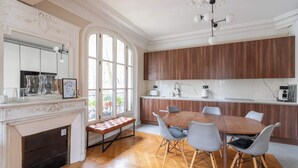 Een eetruimte met een houten tafel en stoelen, een open haard en een groot raam.