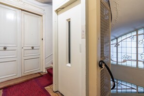 Ein Flur mit rotem Teppich, einer weißen Tür mit Fenster und einer Treppe mit Metallgeländer.