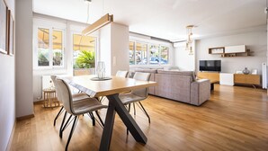 A modern living space with a dining area, sofa, TV, and wooden flooring. - Athenean Riviera Posh Apartment-GF1 (Glifada)