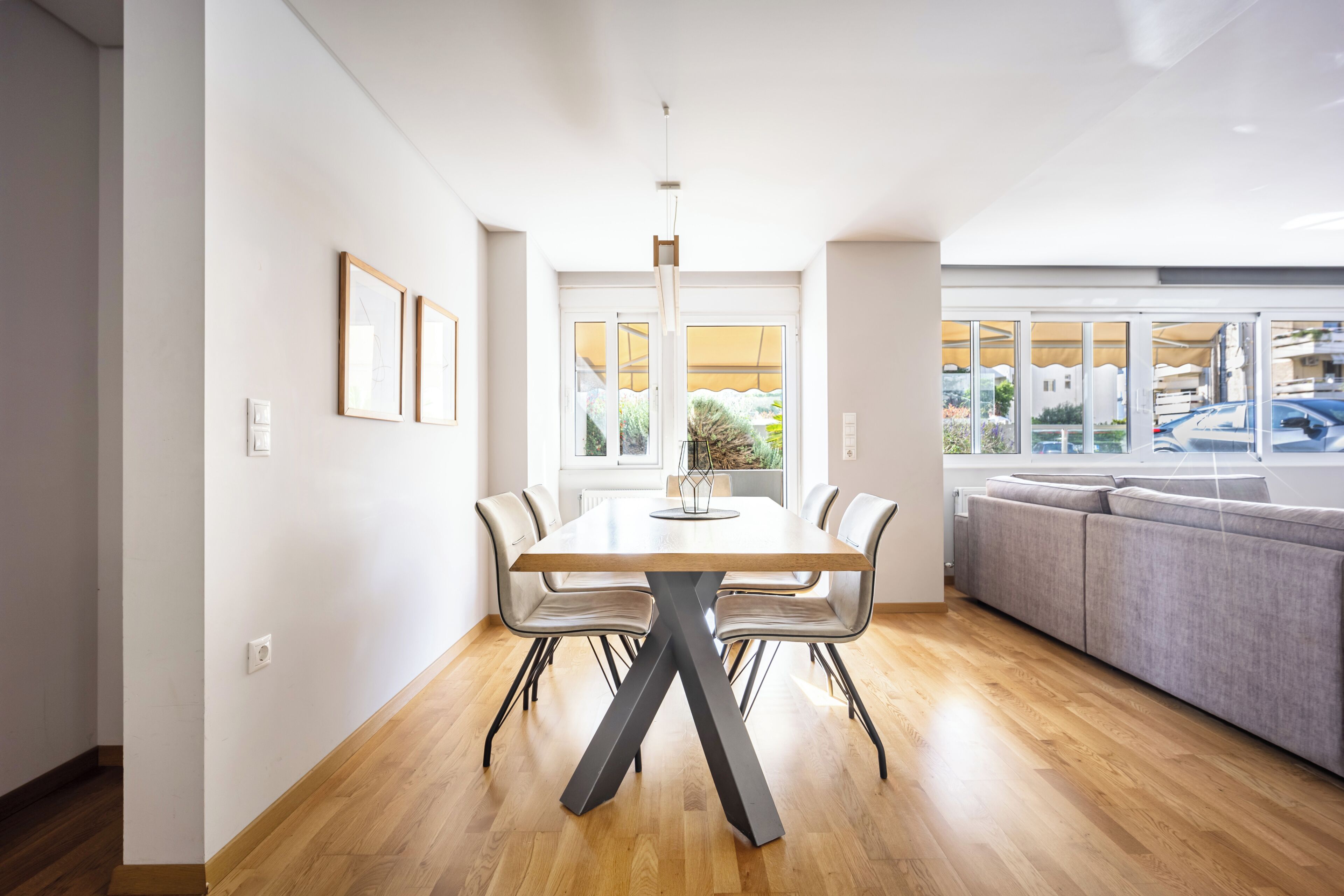 A modern dining area with a wooden table, chairs, and a unique black X-shaped base.