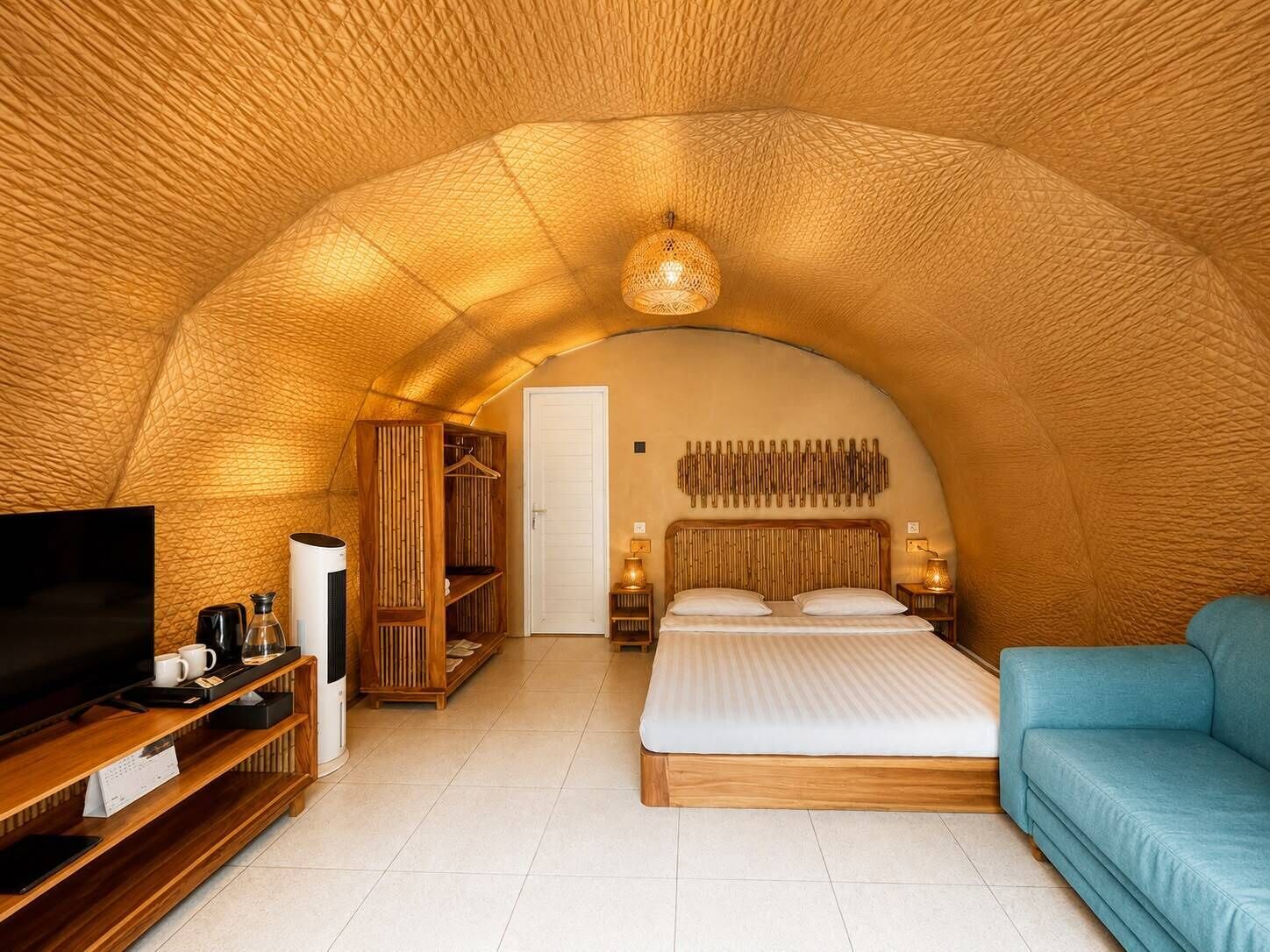 Una habitación acogedora de techo abovedado con una cama, un televisor, un sofá y un armario.