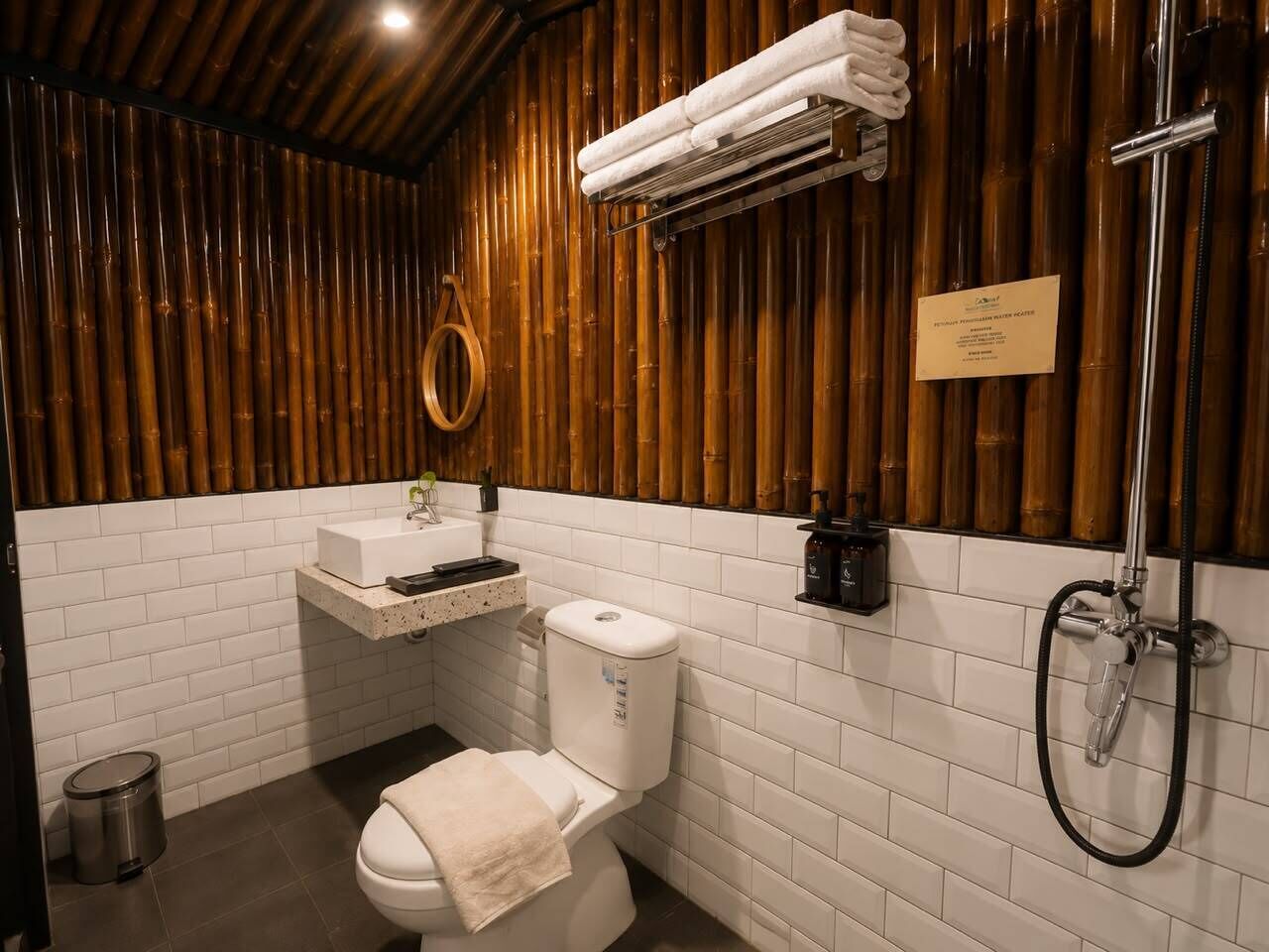 Een badkamer met een bamboe wand, een toilet, een wastafel en een douche.
