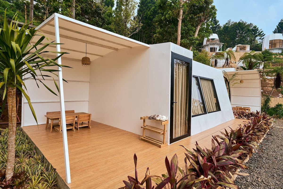 Une maison moderne de plain-pied, dotée d’une terrasse en bois, d’un coin repas et d’une grande porte-fenêtre coulissante.